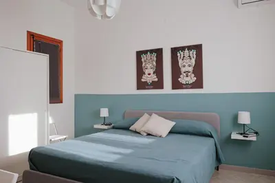 a bedroom with a blue bed with three pictures on the wall at Casa Makira in Terrasini