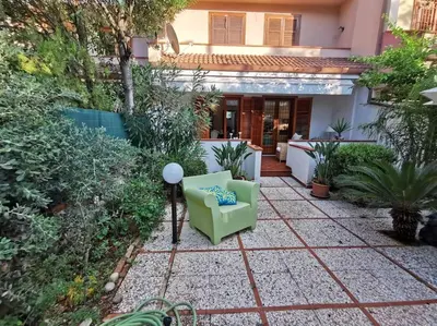 a small garden with a green chair in the yard at Villa Iris - Mondello in Palermo
