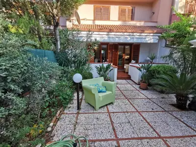 a small garden with a green chair in front of a house at Villa Iris - Mondello in Palermo