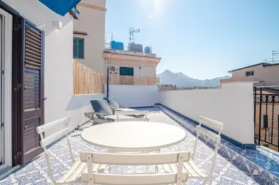 a patio with a wooden table and chairs on a balcony at Zisa Top Romantic Terrace & Private outdoor Jacuzzi in Palermo