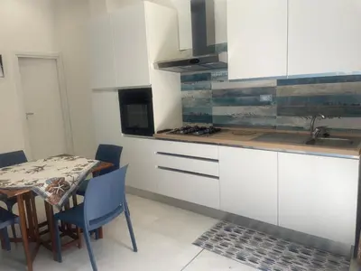 a kitchen with white cabinets and a table with chairs at appartamento francy solare in Castellammare del Golfo