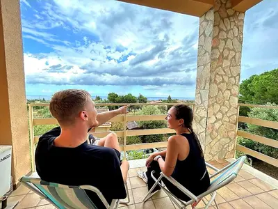 a man and a woman sitting in chairs on a porch at Villa San Lorenzo Sicily in Altavilla Milicia