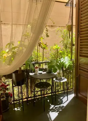 a table and chairs on a balcony with plants at Casa 3D'Oro Palermo in Palermo