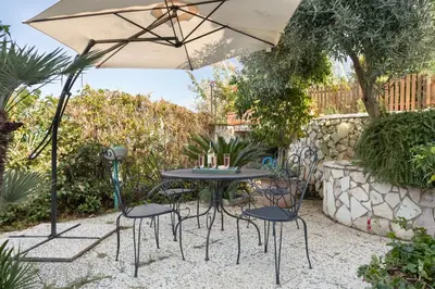 a table and chairs under an umbrella in a garden at Solemar Sicilia - Villa Corallo in Bagheria