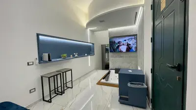 a bathroom with a television and two stools and a door at I Cappuccini Suite in Palermo