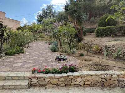 a garden with flowers and a stone wall at Terrazza sul mare Scopello in Scopello
