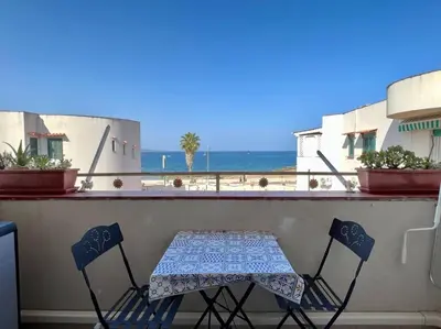 a table and two chairs on a balcony with the beach at Isola delle Femmine Holiday in Isola delle Femmine