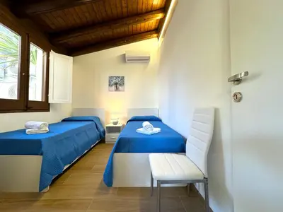 a room with two beds and a chair and a window at Villa Talìa in Carini