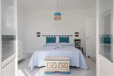 a white bedroom with a bed and a table at Solemar Sicilia - Casa Margherita in Santa Flavia