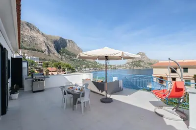 a balcony with an umbrella and a table and chairs at Solemar Sicilia - Casa Margherita in Santa Flavia