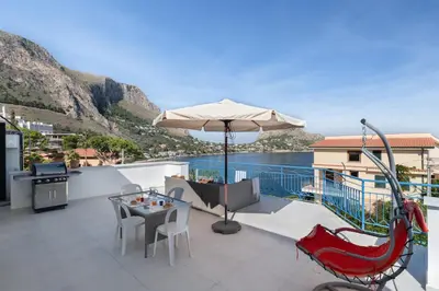 a patio with an umbrella and a table and chairs at Solemar Sicilia - Casa Margherita in Santa Flavia