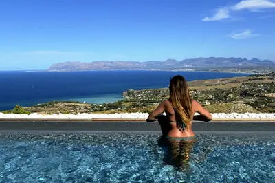 a woman standing in the water looking at the ocean at Villa Fenice in Scopello