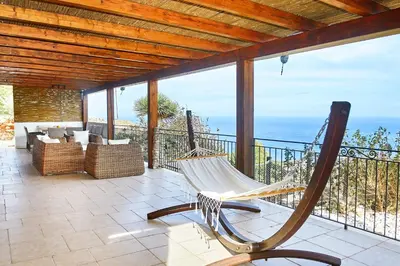 a hammock on a balcony with a view of the ocean at Villa Fenice in Scopello