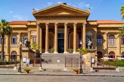 a large building with statues in front of it at Broken column in Palermo