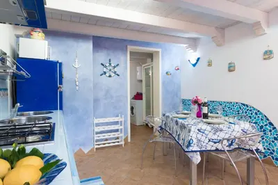 a kitchen with a table and a blue and white wall at Cambusa del Capitano in San Vito lo Capo