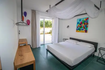 a bedroom with a bed and a table and a window at Hotel Arte Mare in San Vito lo Capo