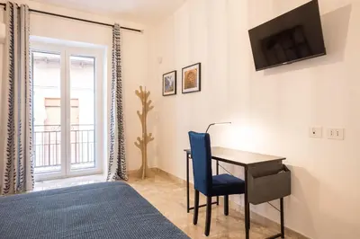 a bedroom with a desk and a tv on a wall at Il gabbiano a Ballarò in Palermo
