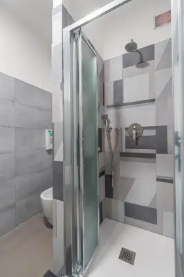 a shower with a glass door in a bathroom at MolteVolte Rooms in Palermo