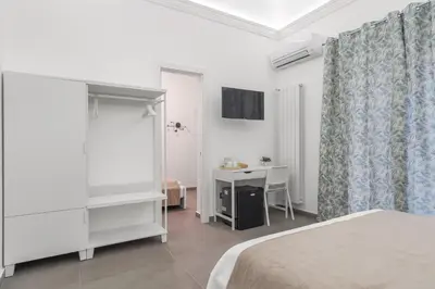 a white bedroom with a bed and a desk at MolteVolte Rooms in Palermo
