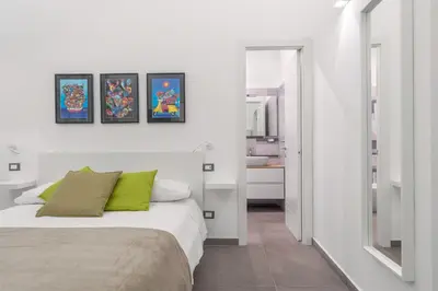 a white bedroom with a bed and a mirror at MolteVolte Rooms in Palermo