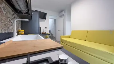 a living room with a yellow couch and a table at Aura di Grecale in San Vito lo Capo