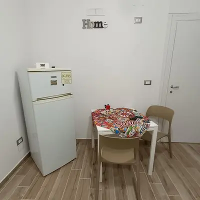a small kitchen with a table and a refrigerator at Casa alla Stazione in Palermo