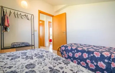 a bedroom with a bed with a floral bedspread and a mirror at Lovely Home In Piane Vecchie,Lascari in Lascari