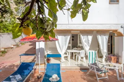 a patio with chairs and an umbrella and a table at Casa in Villa a Mondello-700m dal mare in Palermo