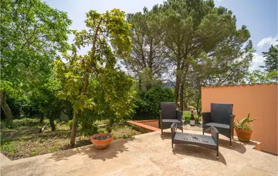 a patio with two chairs and a table and trees at Salvia in San Giuseppe Jato