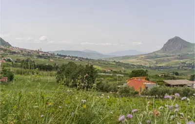 a small village in a field with mountains in the background at Salvia in San Giuseppe Jato