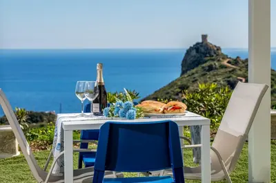 a table with two chairs and a bottle of wine at Villa Holidays in Torre Bennistra in Scopello