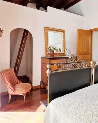 a bedroom with a bed and a chair and a mirror at Casa Al Plumbago in Termini Imerese