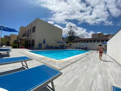a man walking by a swimming pool in a building at Coral sea B2 in San Vito lo Capo