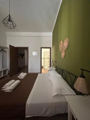 a bedroom with two beds and a green wall at GREENHOME in Palermo