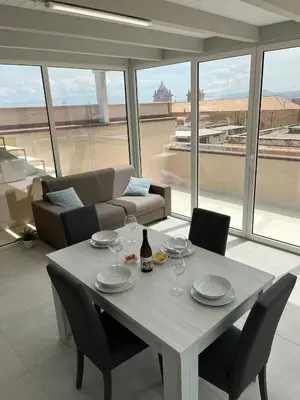 a table with a bottle of wine and chairs in a living room at La Terrazza sul Golfo in Castellammare del Golfo