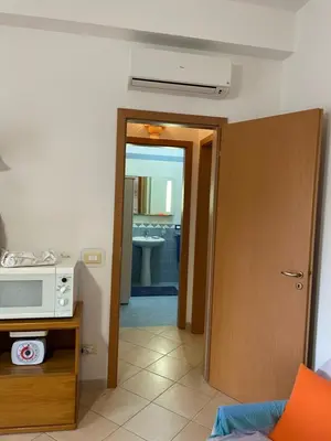 a room with a microwave and a door to a kitchen at Belmare trilocale a piano terra indipendente in San Vito lo Capo