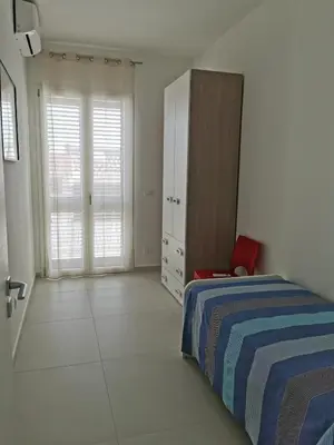 a bedroom with a bed and a cabinet and a red chair at Lovely apartment in Castellammare del Golfo in Castellammare del Golfo