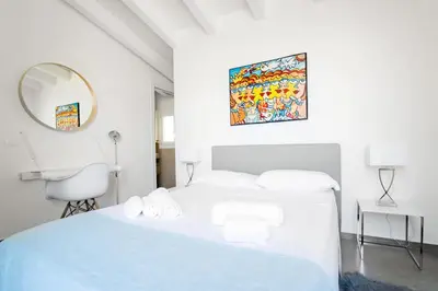 a white bedroom with a white bed and a mirror at Villa Giulietta in Scopello