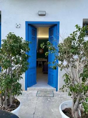 a blue door in a white building with two trees at Casa Chiara in Isola delle Femmine