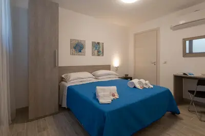 a bedroom with a blue bed with towels on it at I Tre Golfi - Via Salvatore Quasimodo in San Vito lo Capo