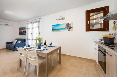 a kitchen and dining room with a table and chairs at I Tre Golfi - Via Salvatore Quasimodo in San Vito lo Capo