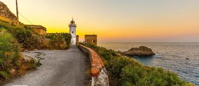 a lighthouse on a path next to the ocean at Da Carmen e Peppe in Santa Flavia