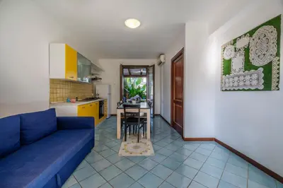 a living room with a blue couch and a kitchen at Casa Vacanza Azzurra 4 in San Vito lo Capo