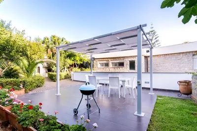 a patio with a table and chairs under a pergola at Mondello luxury villa con piscina in Mondello