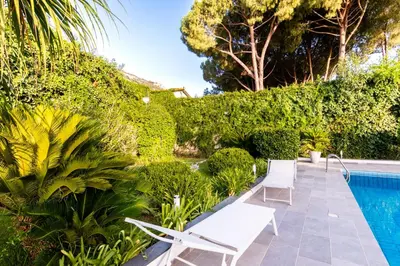 a patio with two white chairs next to a swimming pool at Mondello luxury villa con piscina in Mondello
