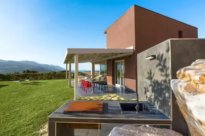 a house with a outdoor kitchen and a table at La Dolce Vita in Castellammare del Golfo