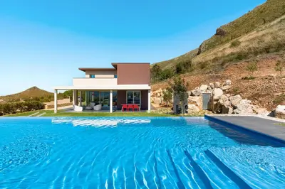 a house with a swimming pool in front of a mountain at La Dolce Vita in Castellammare del Golfo