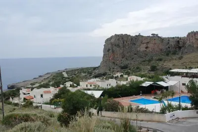 a view of a resort with a mountain at villa Macari in San Vito lo Capo