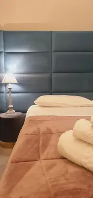 a bedroom with a large bed with a blue headboard at Rosa Apartament in Palermo