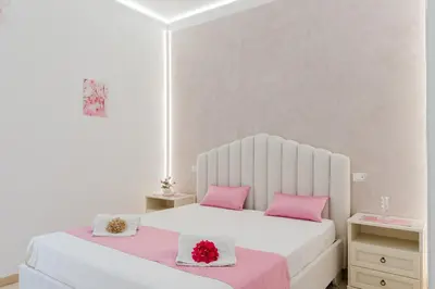 a white bedroom with two beds with pink pillows at B&B Le Ortensie in San Vito lo Capo